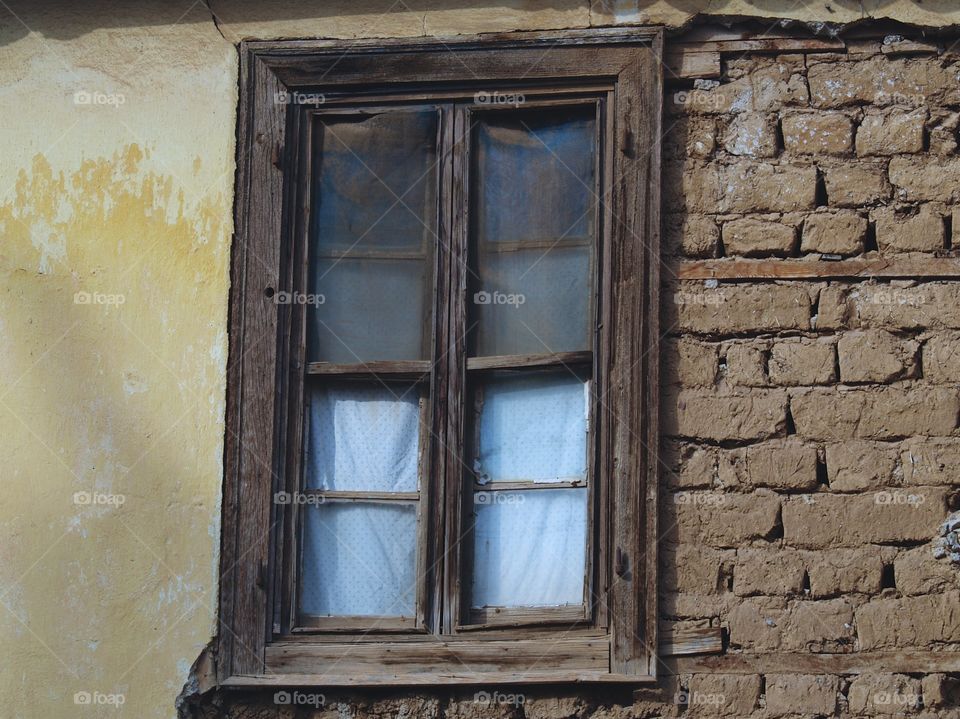 An exterior brick building wall and wooden window in Itea, Greece.
