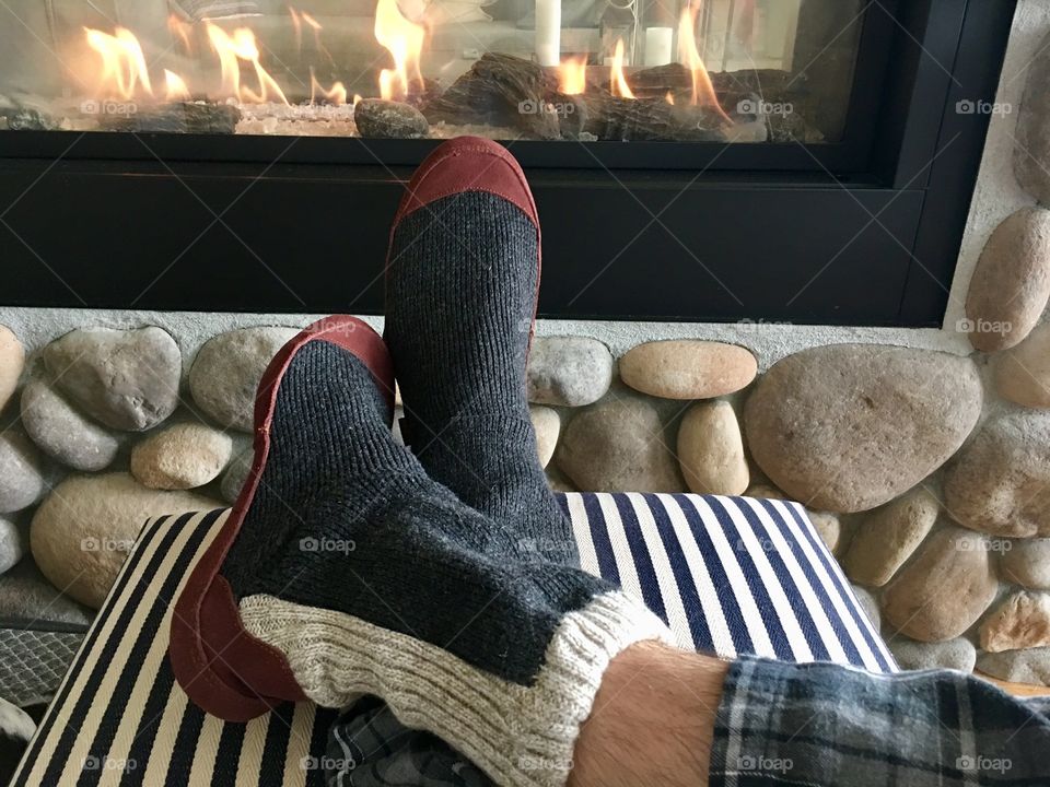 Wearing Acorn slippers by fireplace 