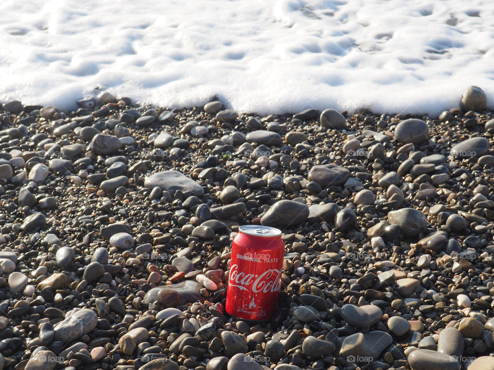 A can of Coca Cola on the stone beach.