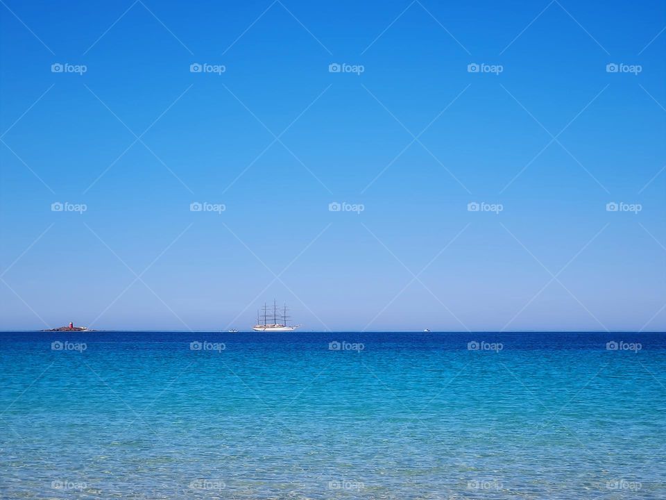 sailing ship in the distance between the sky and the blue sea of ​​Sardinia