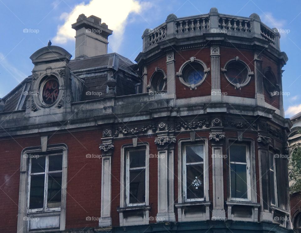 London, UK.  An old building, once a fanciful falls into disrepair.  The words NO WAR are painted In a window.