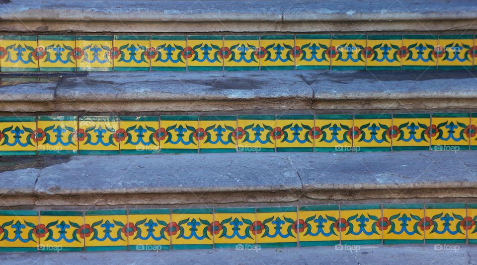 A staircase in San Miguel de Allende, Mexico with ceramic tiled risers leading from a garden to shop.