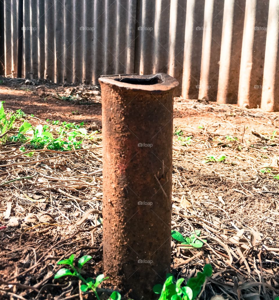 Rusted old iron pipe coming out of ground no purpose 