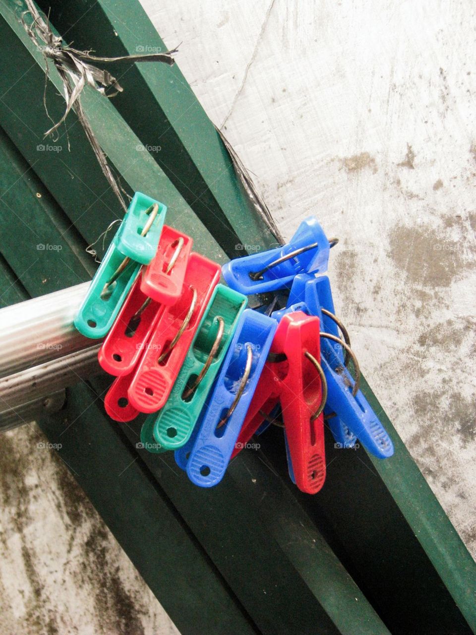 Close-up view of several colorful clothespins hanging on a rope near a green wooden wall