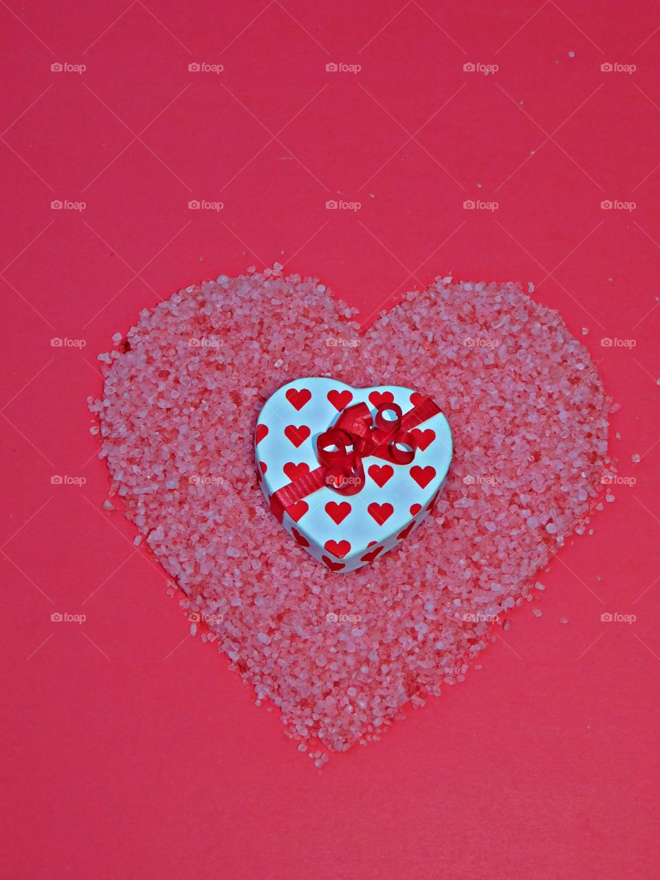 
A flat lay is simply a photo of objects arranged on a flat surface, captured from directly above. Flat lay of a heart decorated box inside a red heart shaped salt design