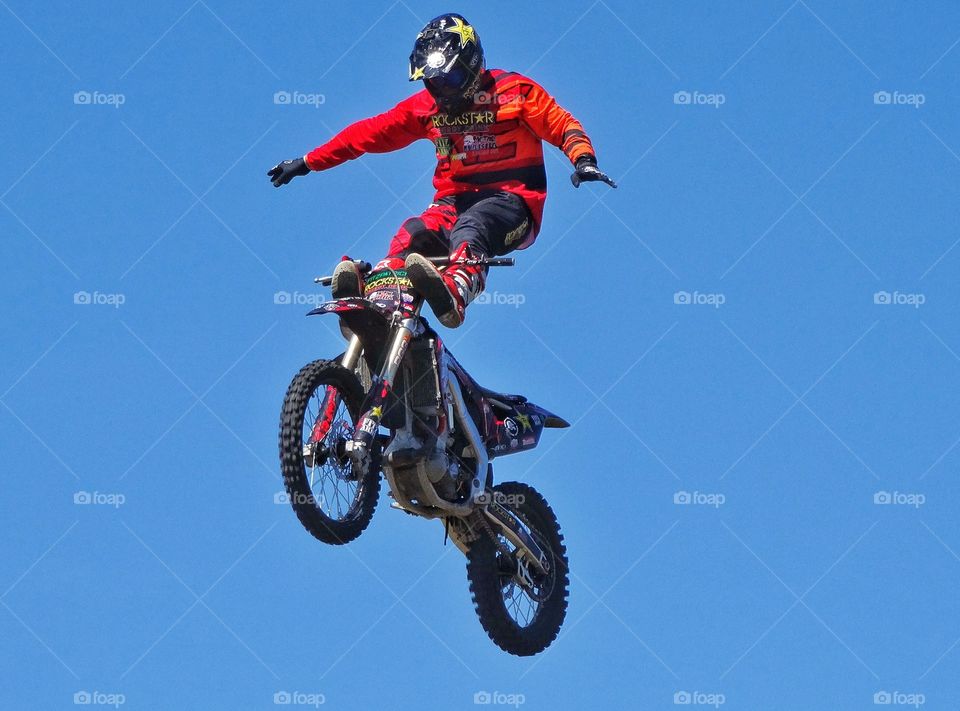 Motorcycle Stunt. Insane Stunt Rider Standing On His Motorcycle In Mid-Air
