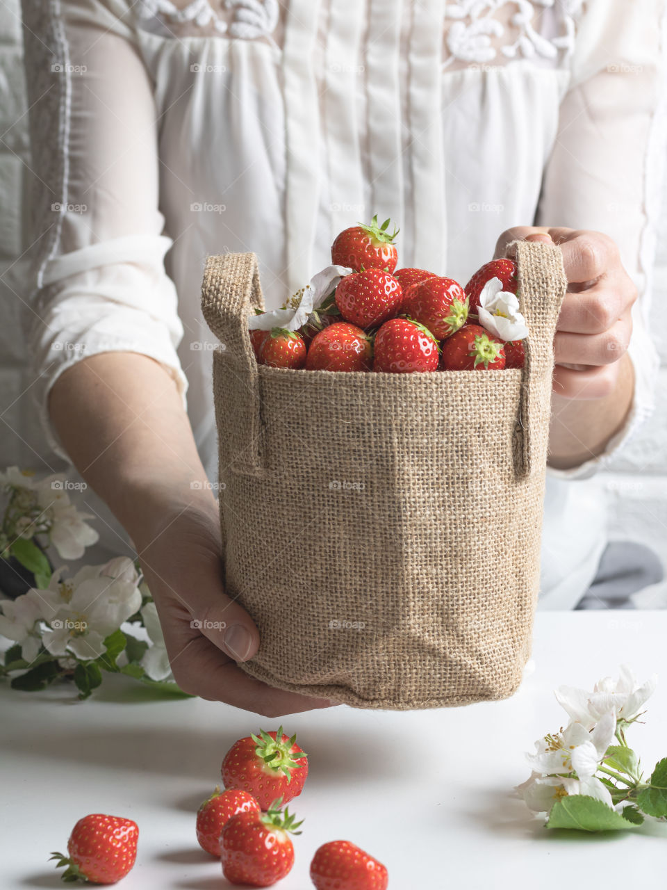 Holding a jute bag full of ripe fresh strawberries 