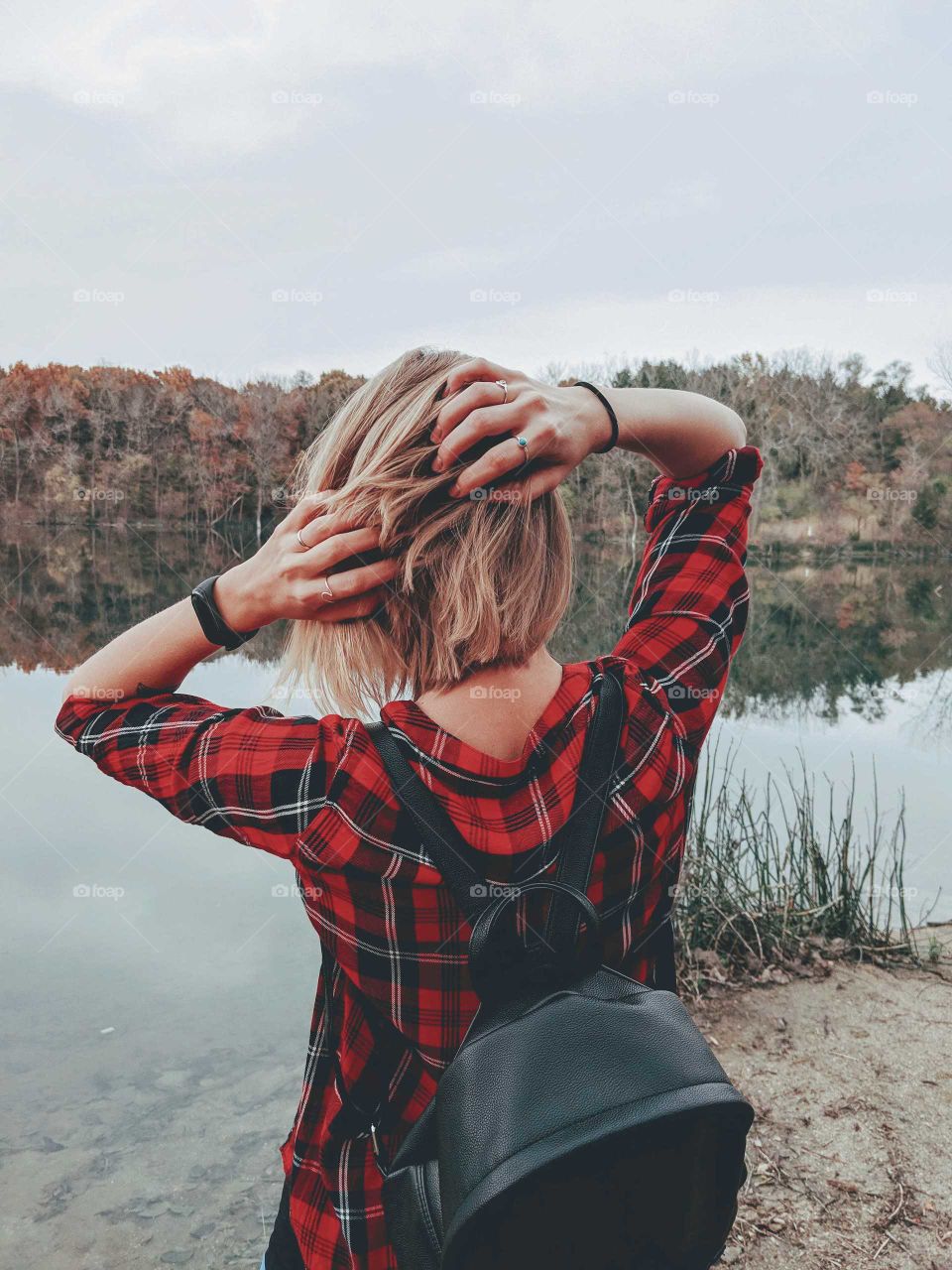 A girl standing in front of a lake looking out at the autumn landscape