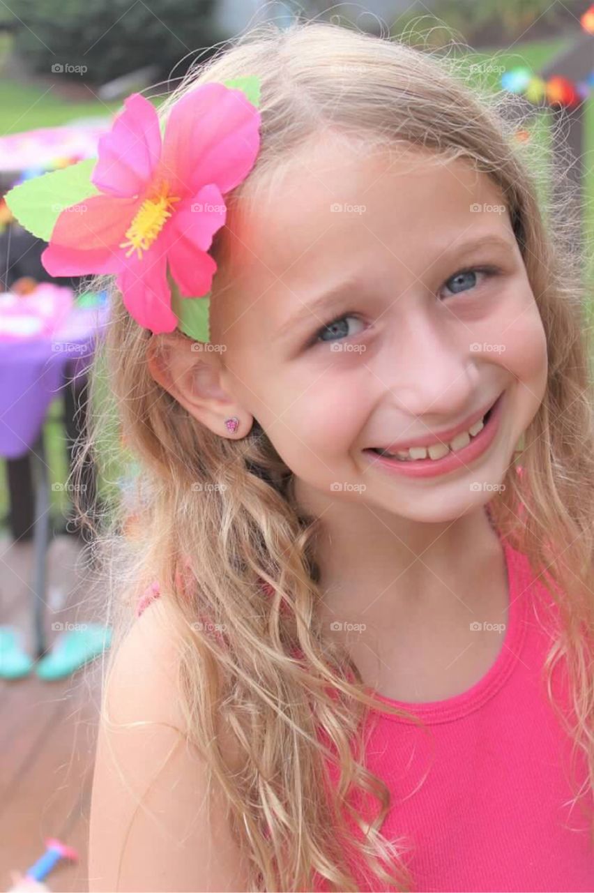 Pretty little blonde haired blue eyed girl with a bright pink hibiscus flower in her hair. Aloha!