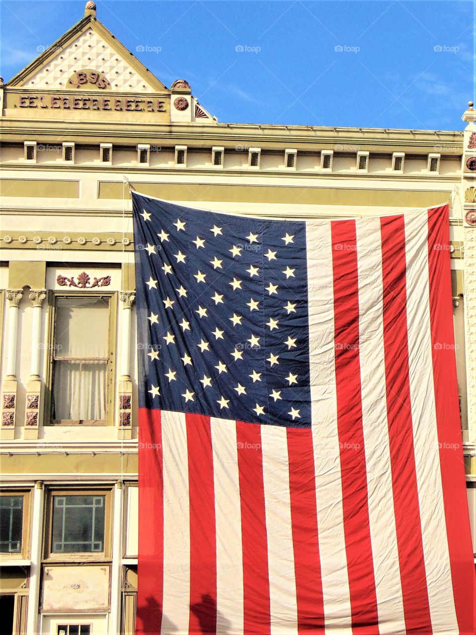 American pride at its' finest...An enormous American flag was displayed proudly on a downtown Small Town main Street during  Veteran's Day ceremonies in Kansas. The buildings in this area are typically from the turn of the century band have honored the Red Hite and Blue for over  a hundred years!