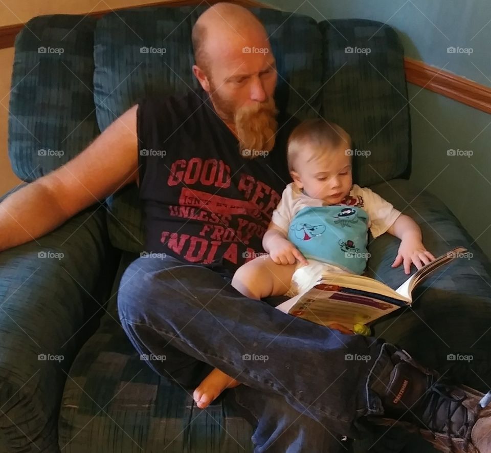 A wonderful father is reading to his beautiful baby boy.