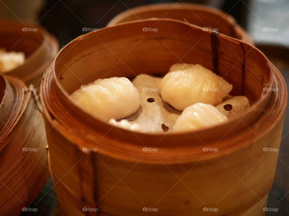 Chinese food. Three dimsum dumplings sit on a bamboo steamer.