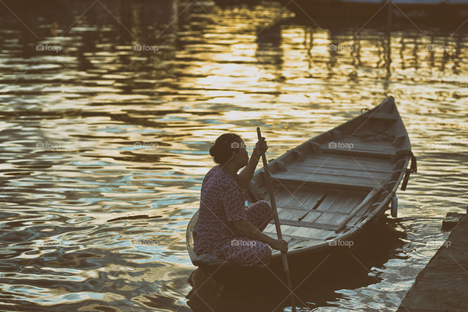 typical scene in Hoi An ancient town, old lady on a boat by the river in central Vietnam