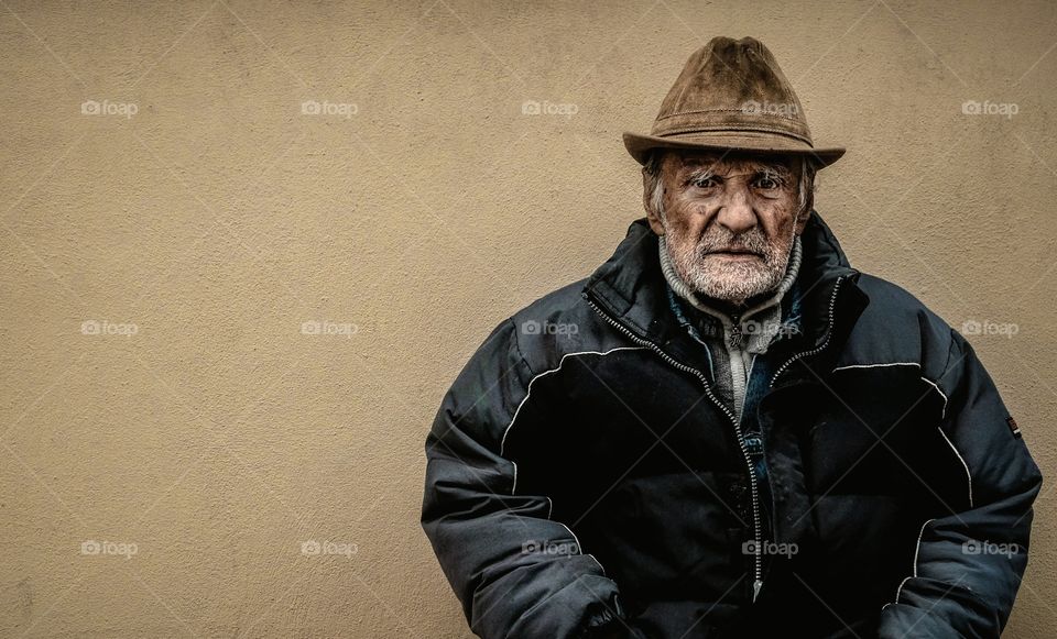 Portrait of an old man against brown wall