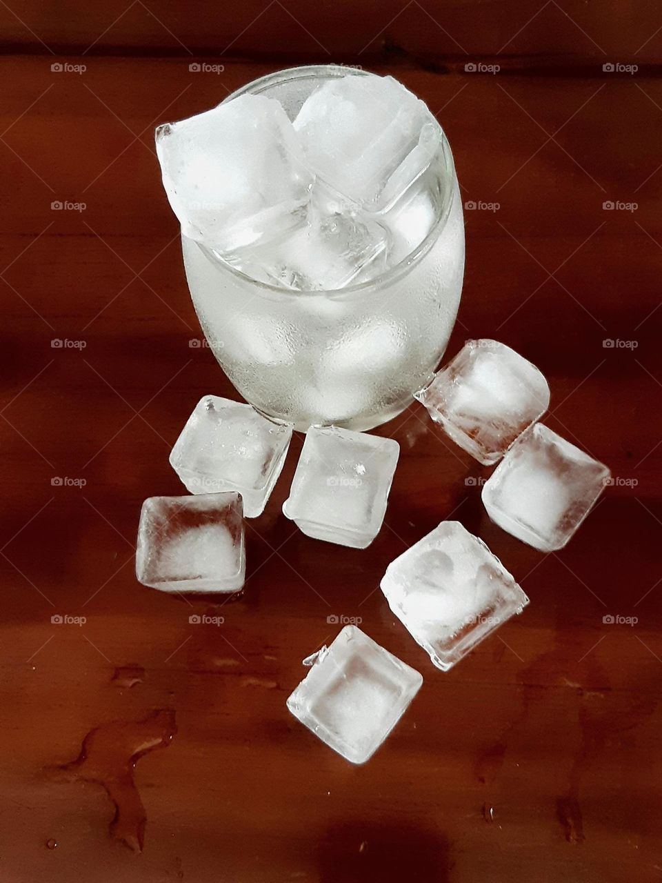 Close up a glass of water with ice cubes isolated on wooden background. Sparkling water