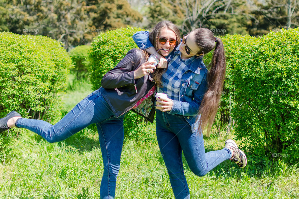 two friends drink coffee and have fun in the park