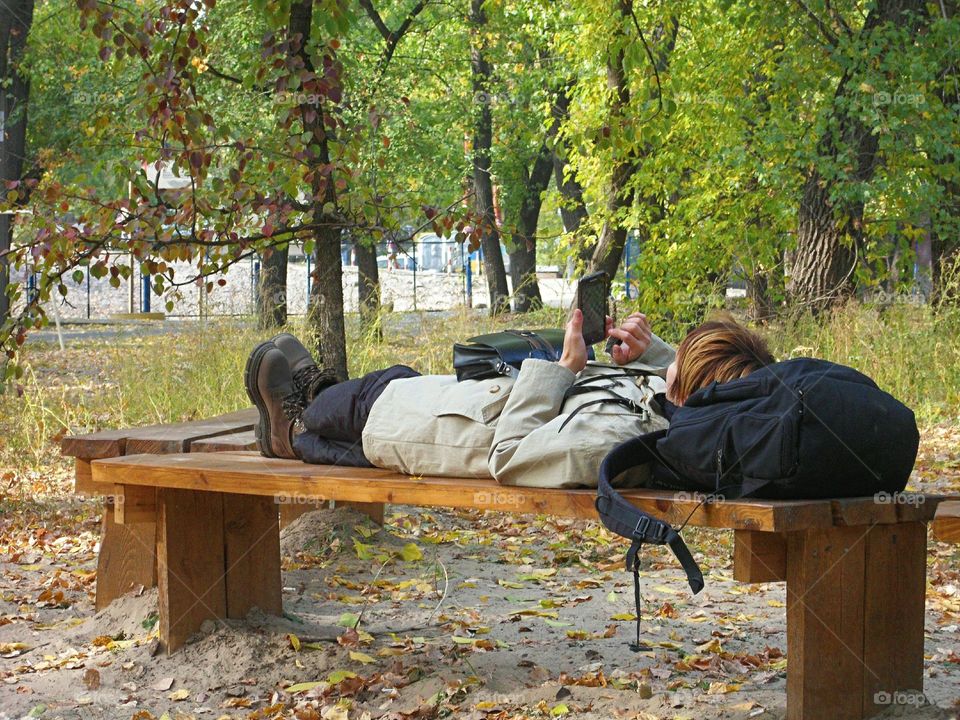 the girl is lying on the bench in the park