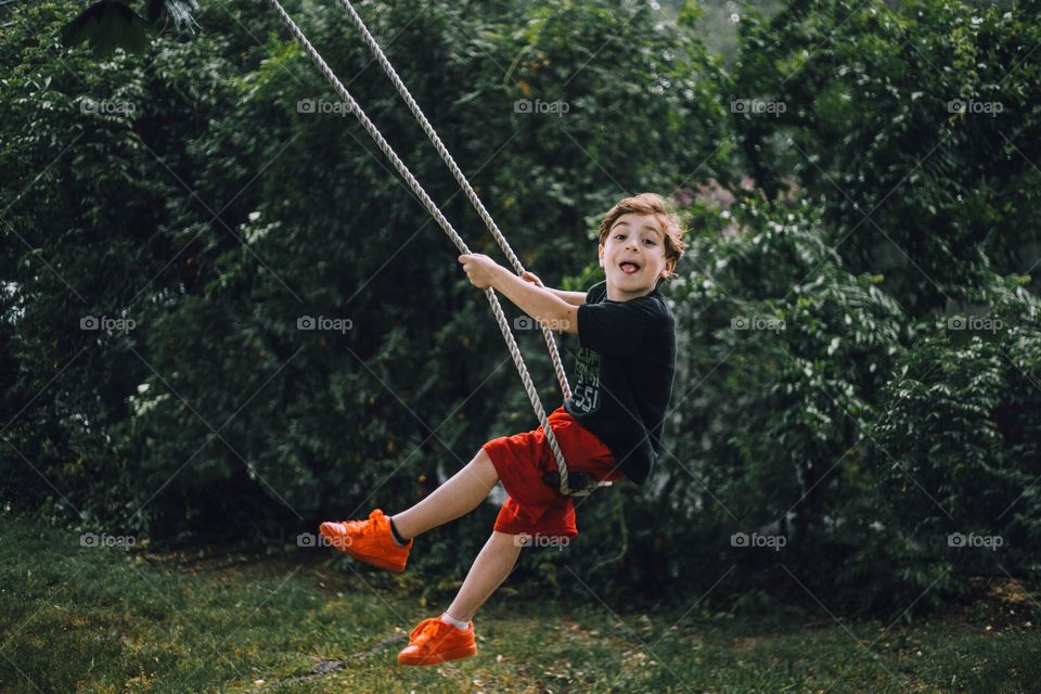 Little boy sticking his tongue out on a swing