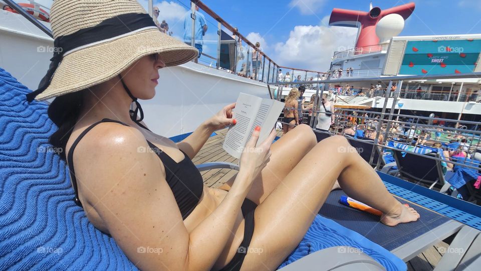 beautiful woman reads a book in bikini on a cruise ship