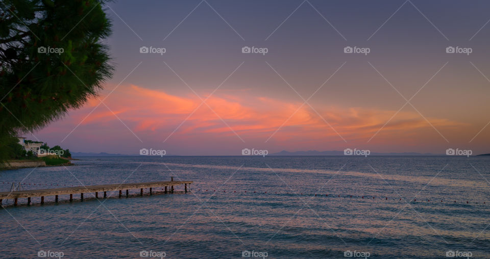 Sunset over sea with jetty.