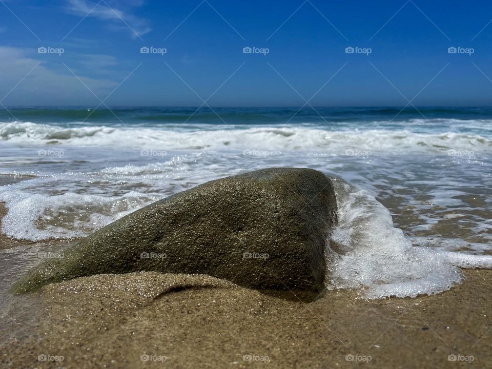 Wave hitting a small rock on Main Beach in Laguna Beach California 