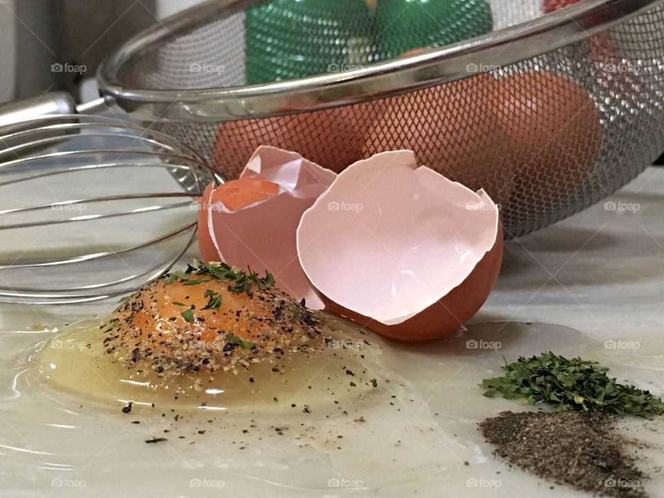 Cracked and seasoned egg on marble kitchen slab, closeup