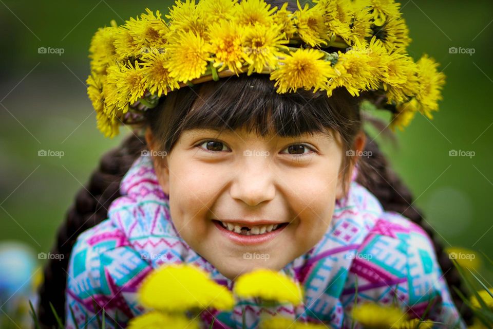Happy little girl in a dandelion wreath