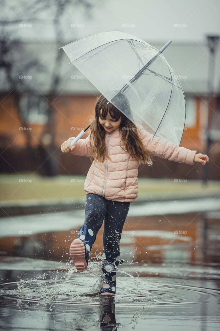 Little girl have fun under the rain.