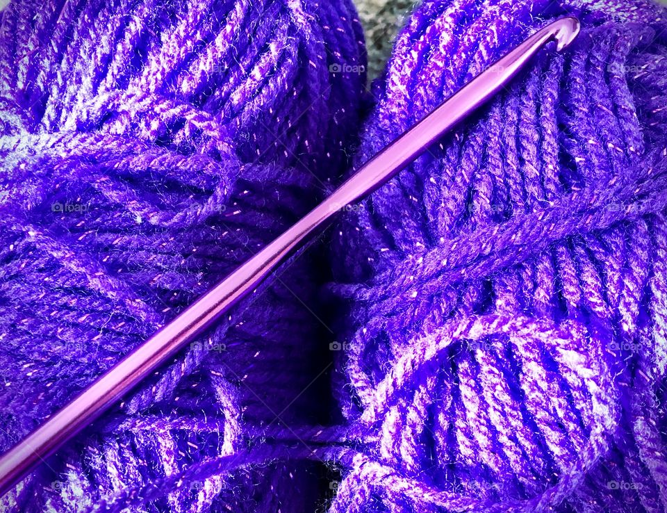 Close up of purple crochet hook with purple sparkle yarn
