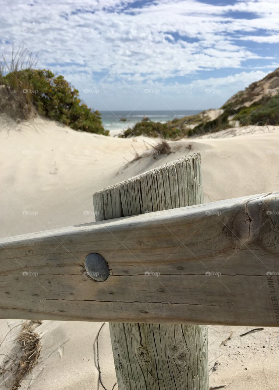 View of secluded pristine beach from vantage of weathered wood handrails railings down to the beach from the cliffs 