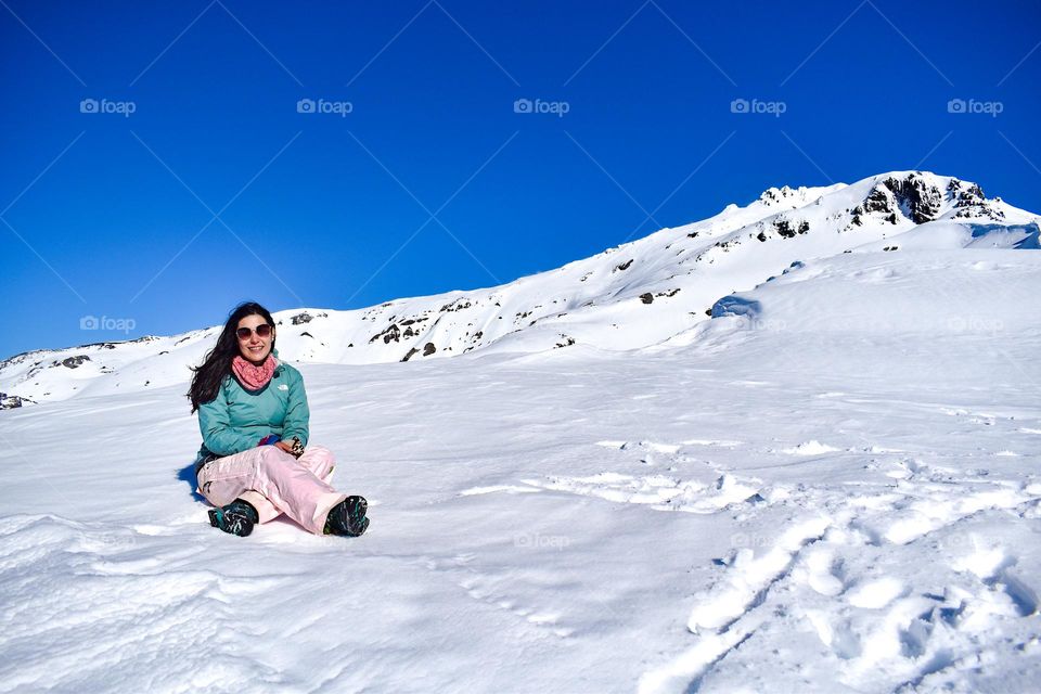 Happy young woman in the top of a snow mountain in winter with a blue sky 