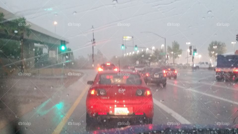 Red car in rain and traffic