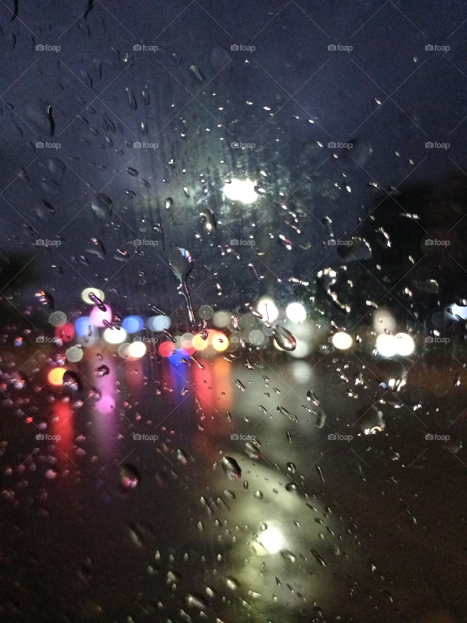 Night photography beautiful view of the street inside the car window in rainy season colourful light with water drops it's looking amazing