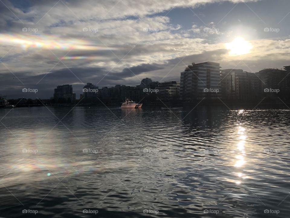 The sun reflecting on copper windows reflecting on a white boat on the water. This photo was taken in the morning
