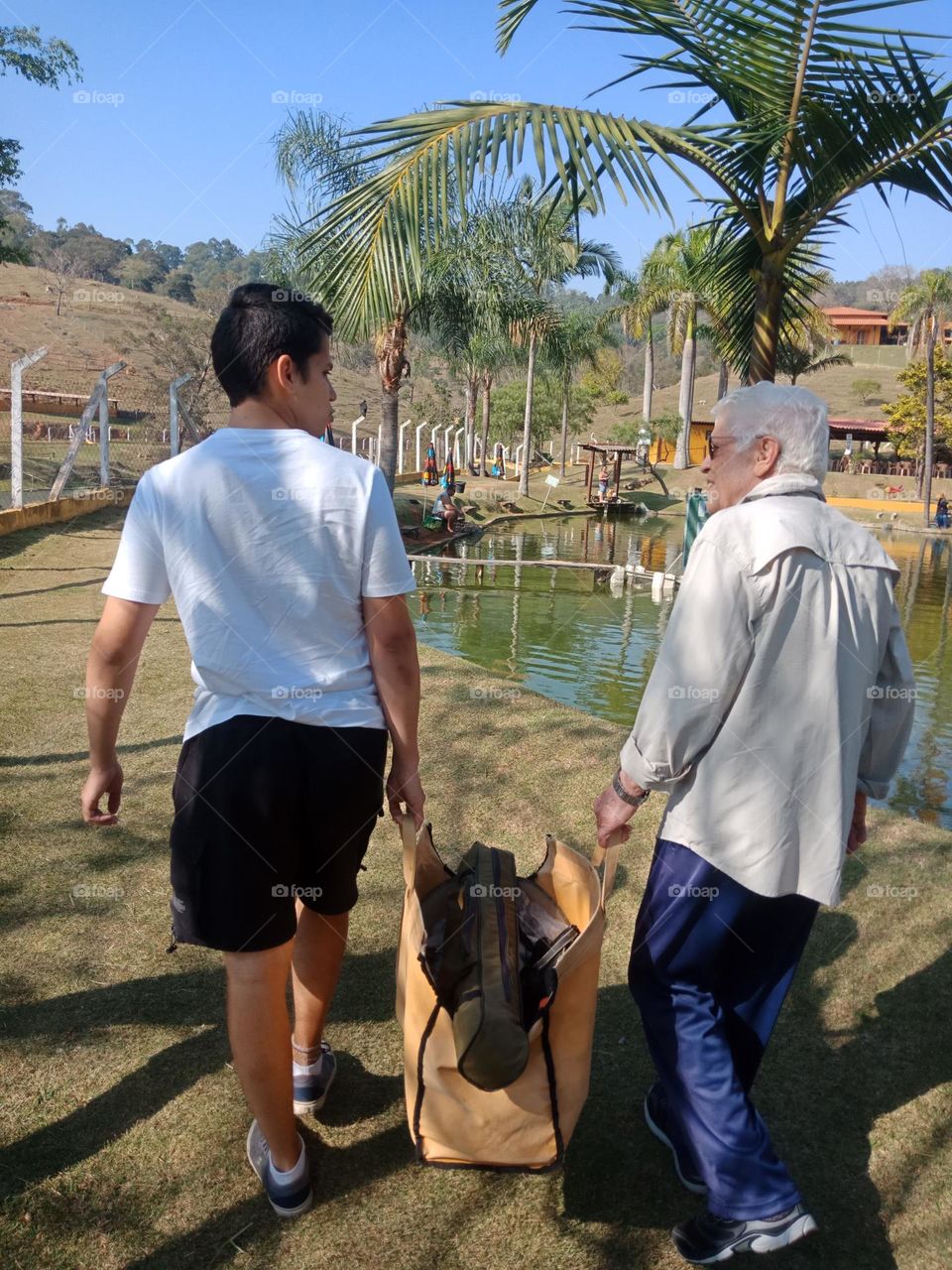 Grandfather and grandson fishing together,  carrying the rods