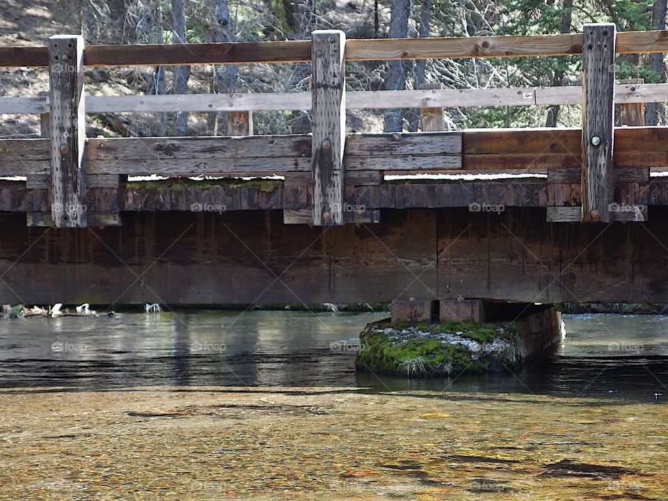 Jack Creek flows under a one-lane wooden bridge in the forests of Central Oregon on a nice sunny day. 