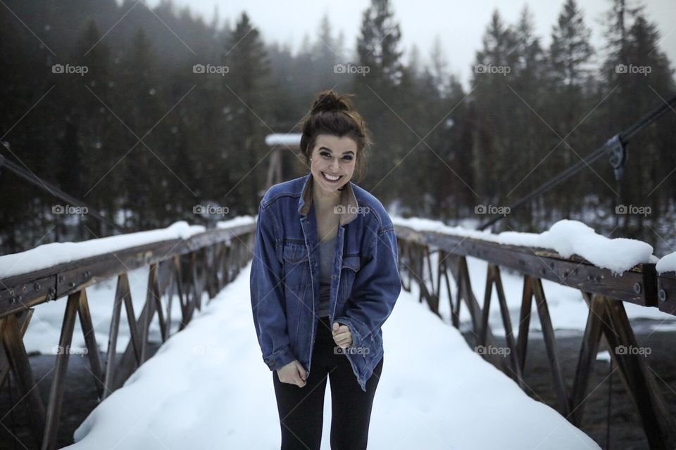 Girl in denim on a cold Montana day crossing a snow covered bridge. 