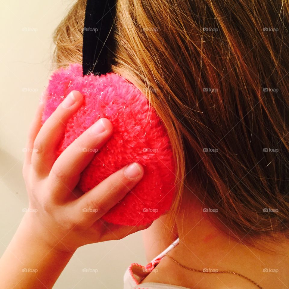 Close-up of a girl holding pink ear muff