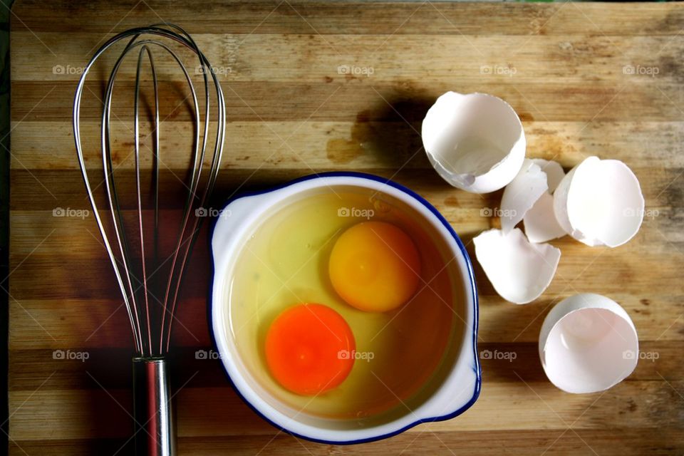 cracked eggs and a whisk on a chopping board