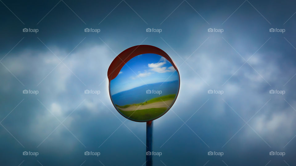 Lollipop landscape. Coastline landscape reflection in the lollipop mirror road sign.