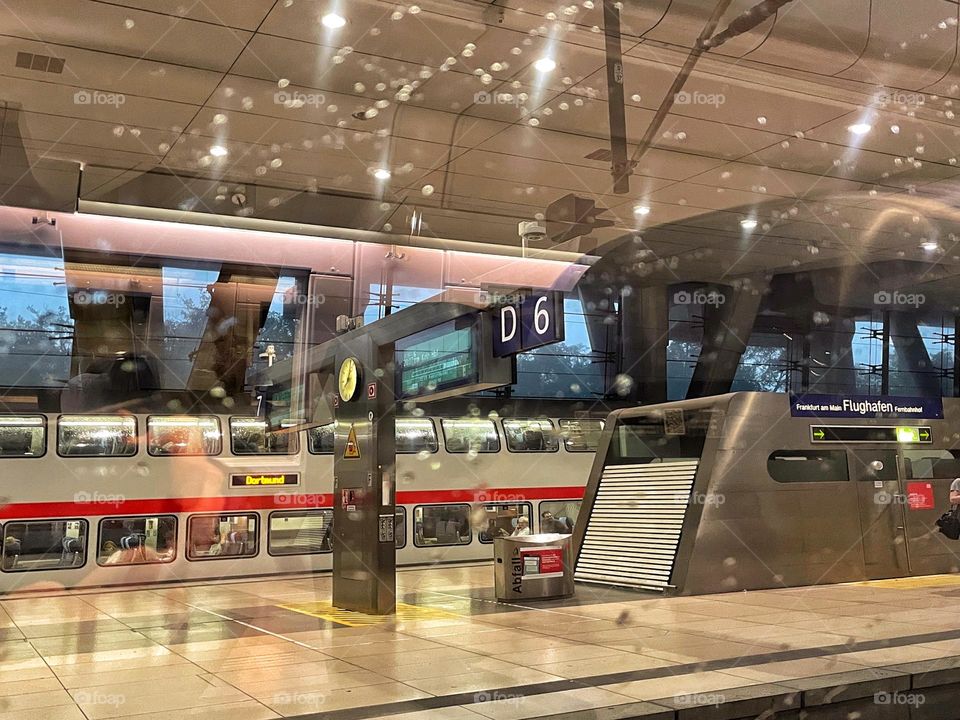 View through a rainy train window into a railway station with a waiting train 