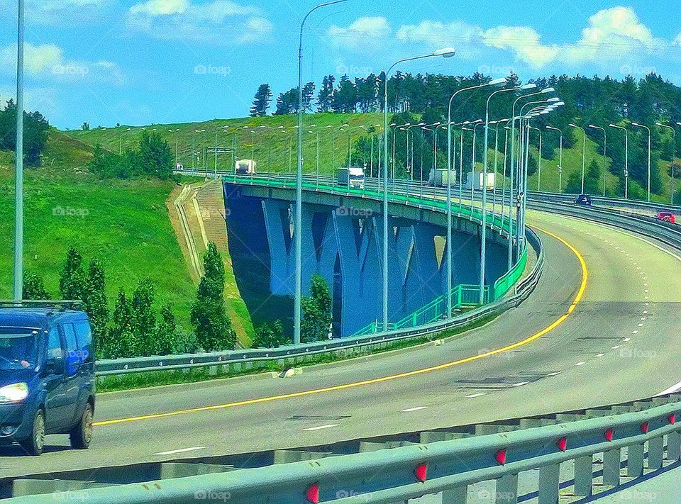 View from the car.  Autobahn road junction through the green mountains.  Bridge for cars