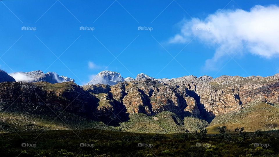 Blue sky above a dusting of snow on top of the mountain