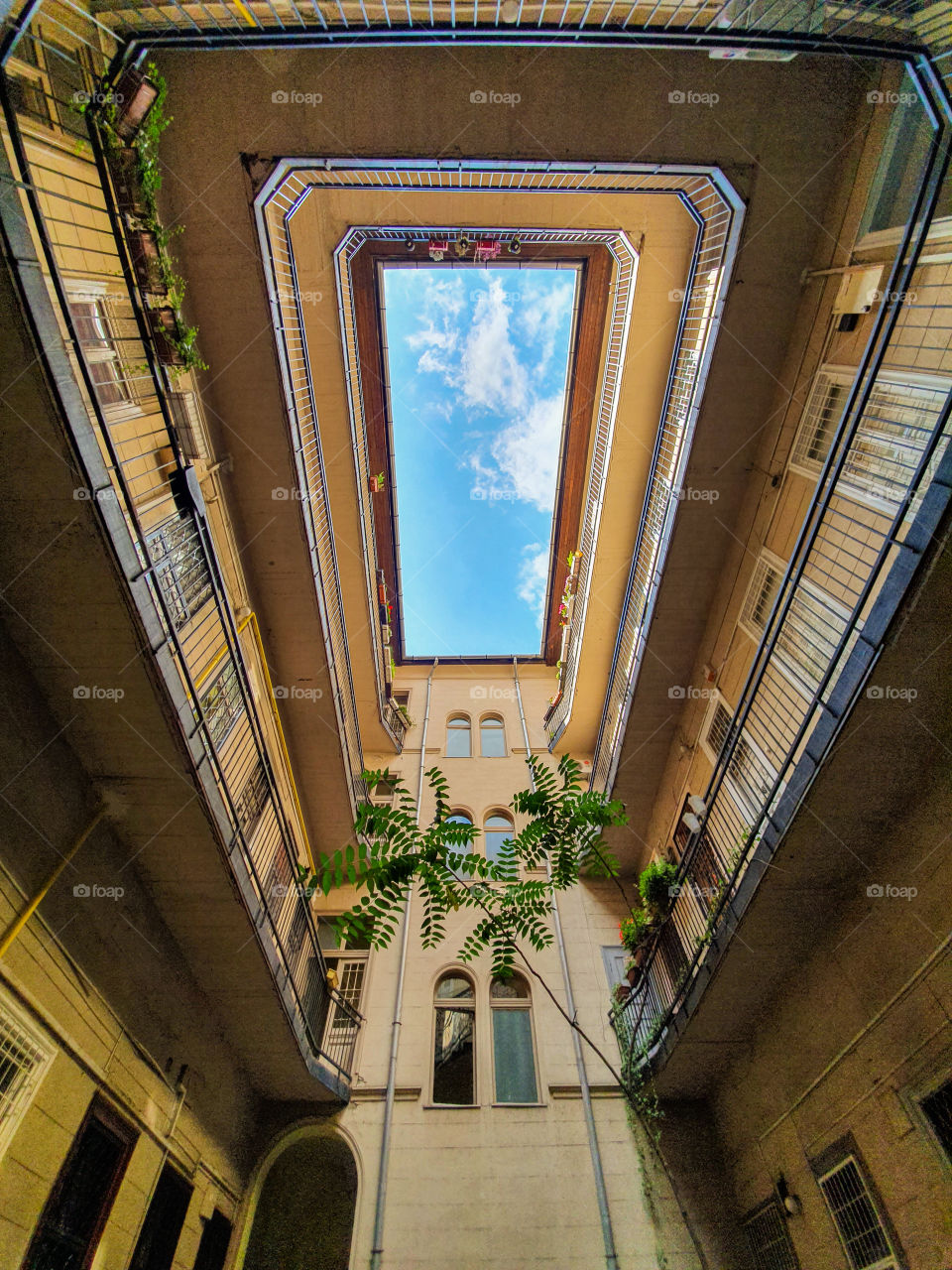 Bottom up view of the sky from an inner courtyard square of a building in Budapest. Geometric view of an inner square of a residential building.