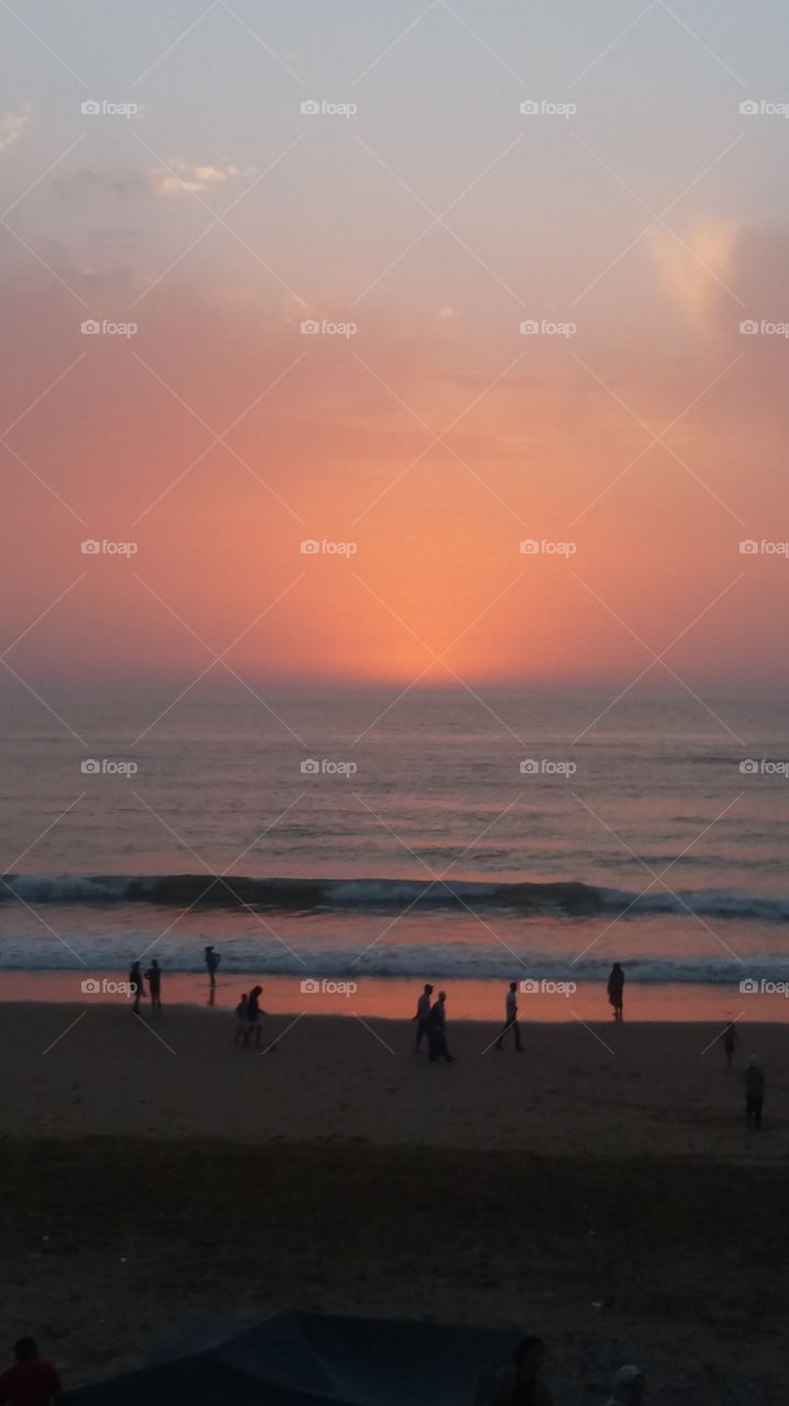 people walking on the beach during the sunset