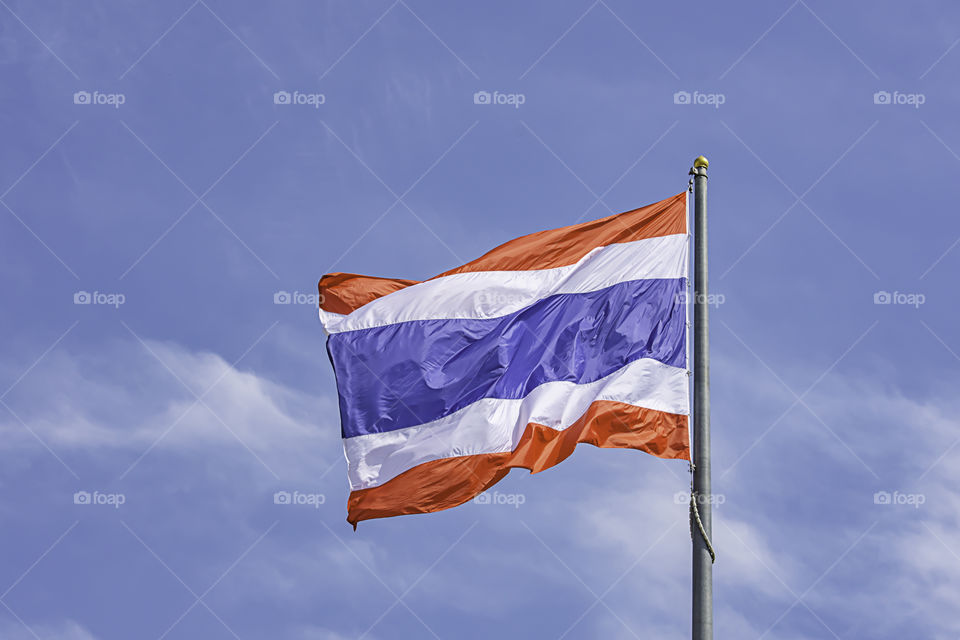 Flag of Thailand on the pole and bright blue sky.