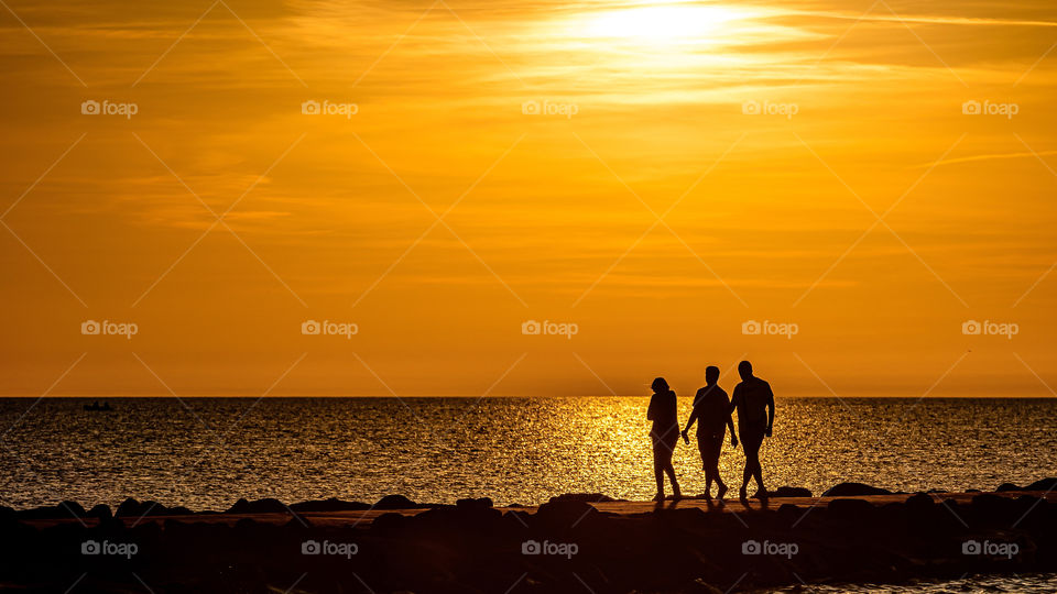 silhouette of people walking on the pier during the golden hour of sunset