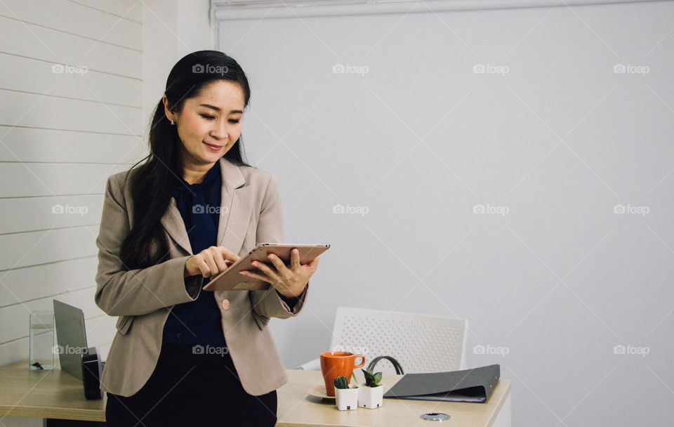 Asian business woman is checking information on her tablet