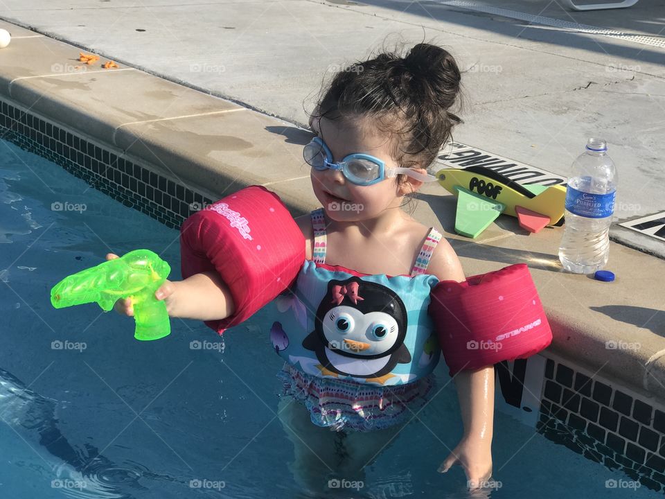 My precious daughter squirting everyone at the pool with a water gun. 