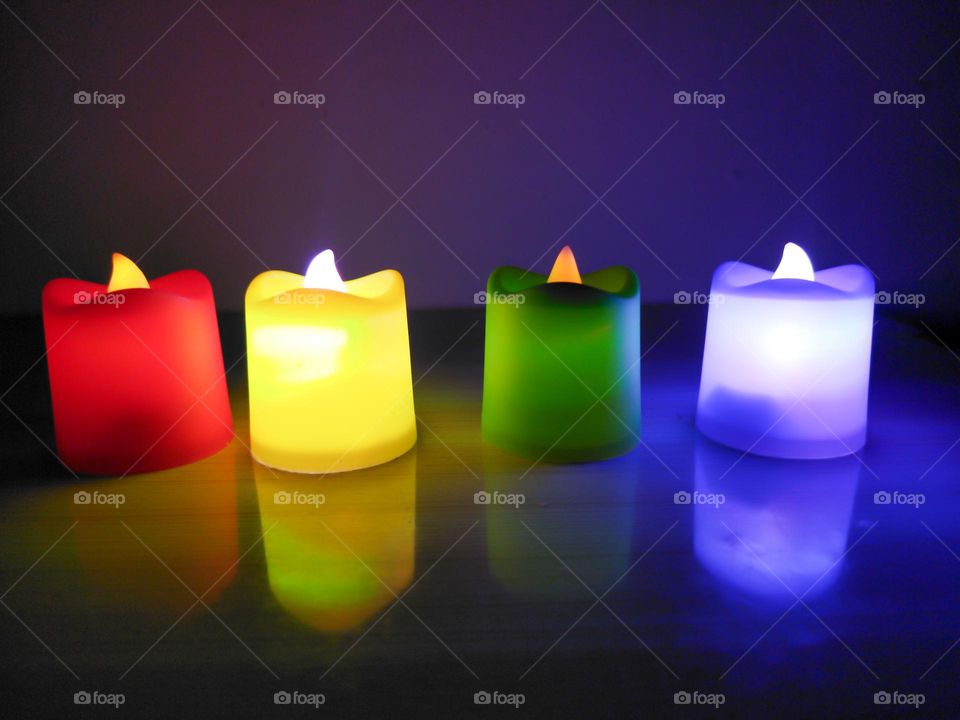 Beautiful candles lit at night with reflection on a wooden table, two of them are high light and two are low light